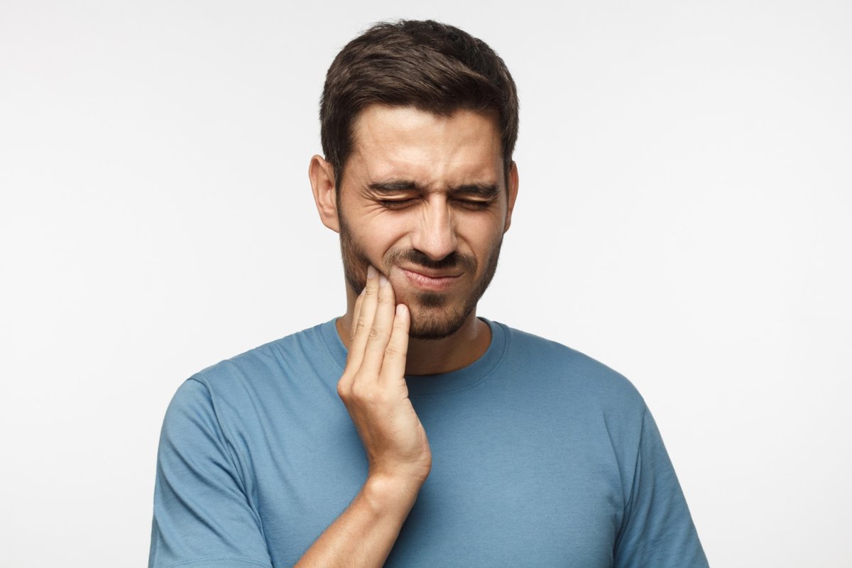 Man holding his jaw in pain, showing signs of a dental emergency and urgent need for care